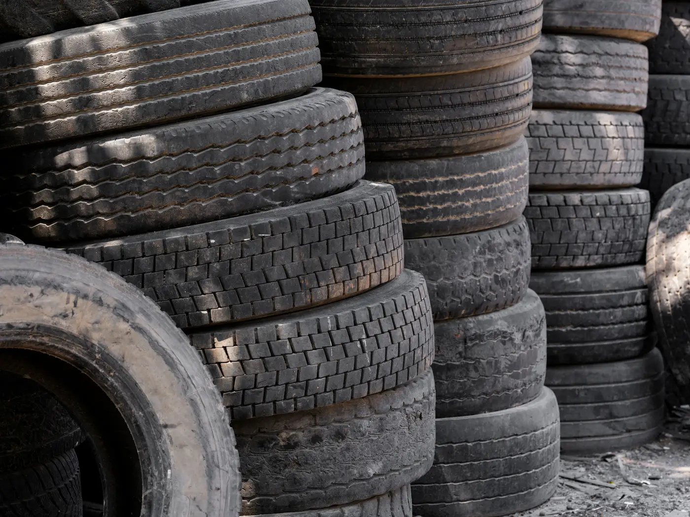 Close stacks of used tires piled outdoors at an industrial yard.